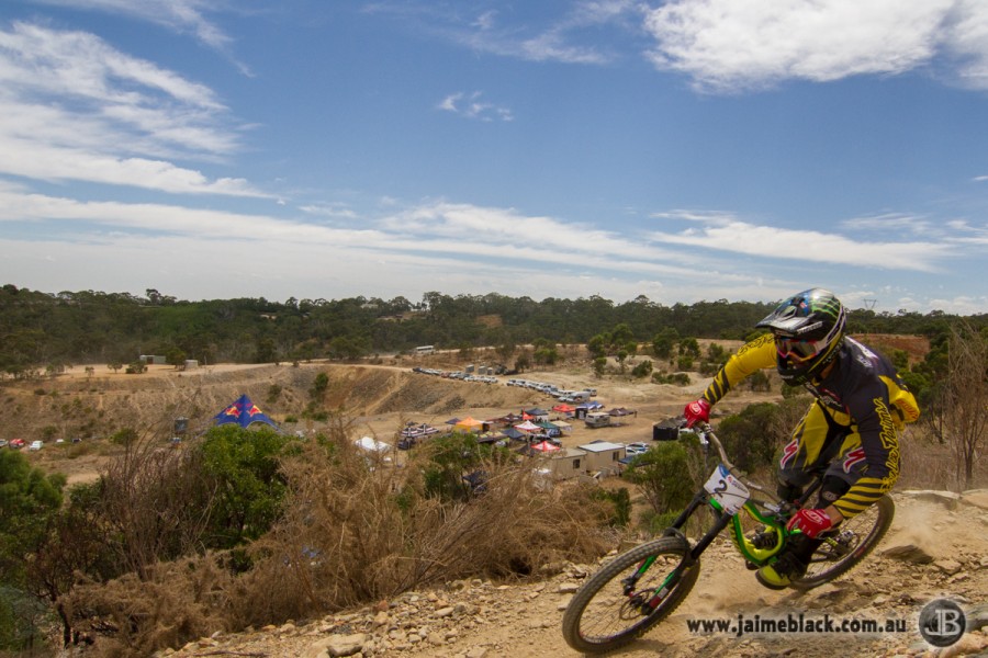 Troy Brosnan blasts past with the pits in the background.